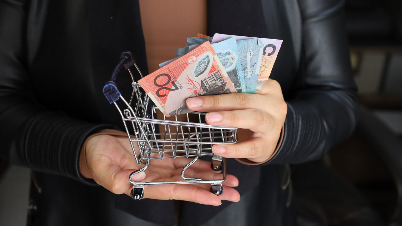 A young Australian looking stressed while holding a high grocery receipt in a supermarket.