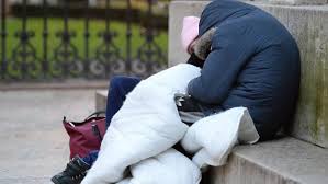 A silhouette of a person sitting on a bench in an Australian city park, representing the homelessness crisis.