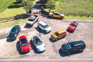 A sleek silver 2026 Porsche 911 GTS driving on a winding mountain road during sunset.
