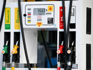 A frustrated Australian driver at a petrol station looking at a fuel pump showing high prices.