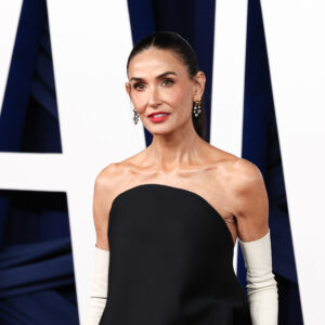 Alt Text: Demi Moore debuts extreme new look on Actor Awards red carpet wearing a black Schiaparelli croc-effect gown and bob.