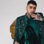 British pop star Zayn Malik looking serious while leaving a venue surrounded by a security team and a large crowd.