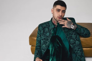 British pop star Zayn Malik looking serious while leaving a venue surrounded by a security team and a large crowd.