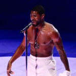 R&B icon Usher performing shirtless on stage, showcasing his incredibly ripped abs and muscular physique under stage lights.
