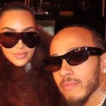 Kim Kardashian and Lewis Hamilton walking together on a sandy beach during their romantic summer family getaway.