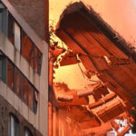 Emergency services surrounded by fallen brick rubble and crushed vehicles on Wattle Street during Ultimo collapse.