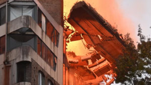 Emergency services surrounded by fallen brick rubble and crushed vehicles on Wattle Street during Ultimo collapse.