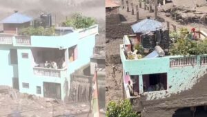 A mint-green house standing intact in Nepal surrounded by raging brown floodwaters and river debris.